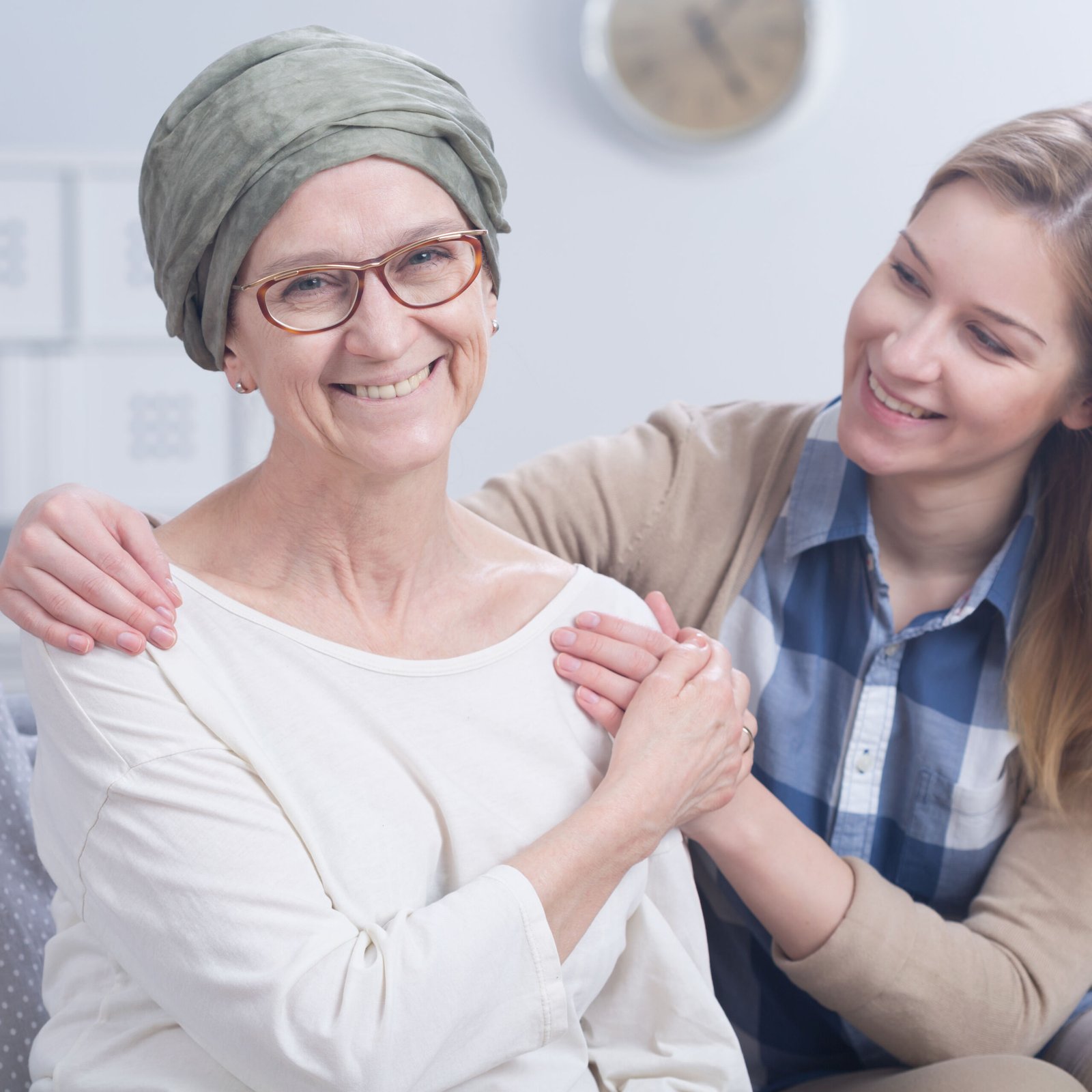 Smiling cancer woman with headscarf embraced by young happy girl